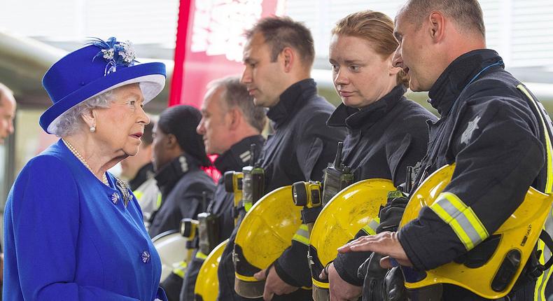 Britain's Queen Elizabeth II, left, meets firefighters during a visit to the Westway Sports Centre which is providing temporary shelter for those who have been made homeless by the fire at Grenfell Tower.