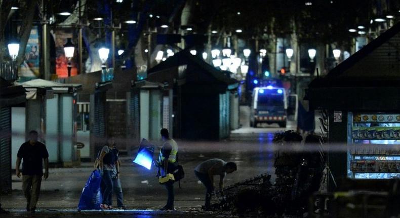 Policemen check the area after towing away the van which ploughed into the crowd, killing at least 13 people and injuring around 100 others on Las Ramblas in Barcelona