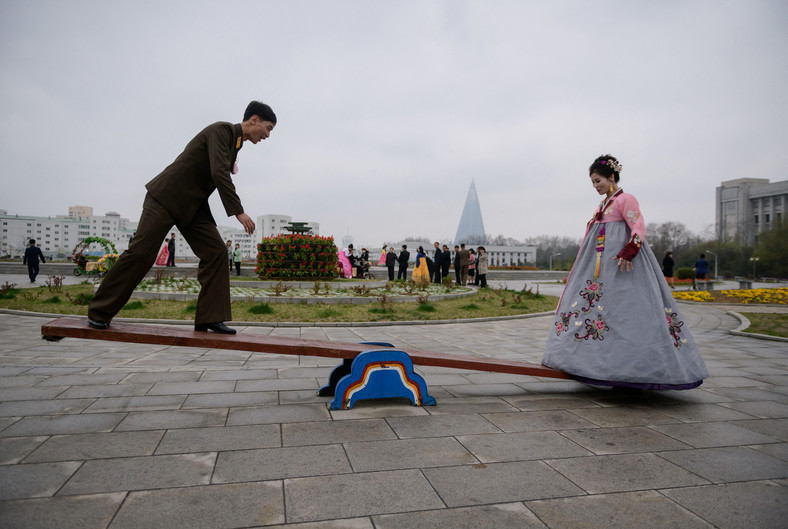 Para młoda pozuje na huśtawce podczas ślubnej sesji zdjęciowej w parku w Pjongjangu 18 kwietnia 2019 r.