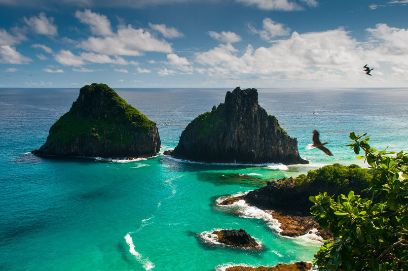 Fernando de Noronha – archipelag o najpiękniejszych plażach Jeśli nie mieszkasz w Ameryce Południowej, prawdopodobnie nigdy nie słyszałeś o Fernando de Noronha. Ale jeżeli kiedykolwiek pojawi się okazja odwiedzenia tego miejsca – nie wahaj się ani przez chwilę. Fernando de Noronha jest archipelagiem 21 wysp i wysepek rozsianych na Oceanie Atlantyckim, 354 km od wybrzeża Brazylii. Ze względu na delikatny ekosystem, wpisany został na listę światowego dziedzictwa UNESCO. To miejsce to raj, którego władcami są mieszkające tu ogromne żółwie – ich wielkość sięga nawet 1,5 metra. Zwierzęta są oswojone z ludźmi, ale nie wolno ich nadto niepokoić, dlatego maksymalna ilość odwiedzających to 460 osób jednocześnie. Na archipelagu znajdują się także dwie najlepsze plaże w całej Brazylii: Praia do Leão i Baía do Sancho. Zachwyceni nimi będą nie tylko plażowicze ale i nurkowie, których zaskoczy krystalicznie czystość tutejszych wód, dających schronienie ponad dwustu gatunkom ryb, pięciu gatunkom rekinów, żółwiom morskim i delfinom. Źródło: r.pl/brazylia >>