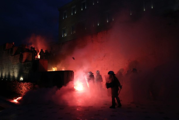 Riot police stand among flare smoke on the Tomb of the Unknown Soldier burns during clashes outside 