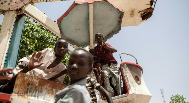 Children orphaned by Boko Haram Islamists play on a spinning wheel at an abandoned amusement park in Maiduguri, Nigeria