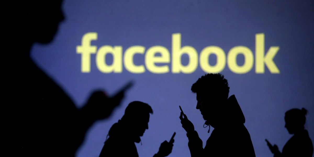 FILE PHOTO: Silhouettes of mobile users are seen next to a screen projection of Facebook logo in this picture illustration