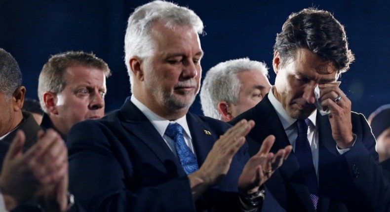 Canada's Prime Minister Justin Trudeau (R) wipes a tear as he stands beside Quebec Premier Philippe Couillard during funeral services for three of the victims of the deadly shooting at the Quebec Islamic Cultural Centre, in Montreal, February 2, 2017