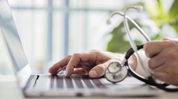 Doctor entering patient notes on laptop in surgery