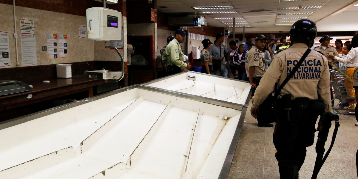 Police officers walk inside a supermarket in Caracas, Venezuela, June 30, 2016.