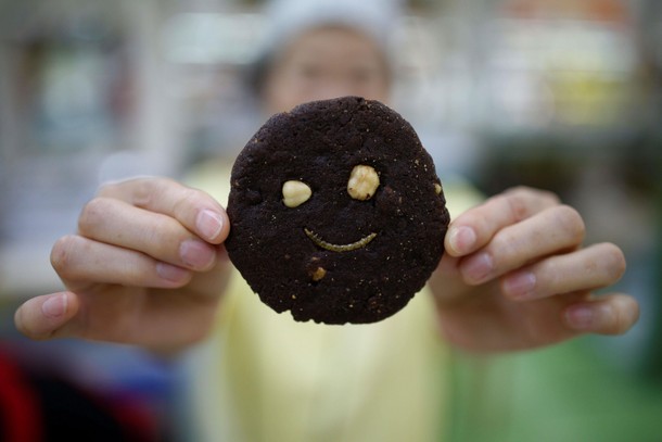 A sales assistant poses for photographs with a mealworm cookie in Seoul