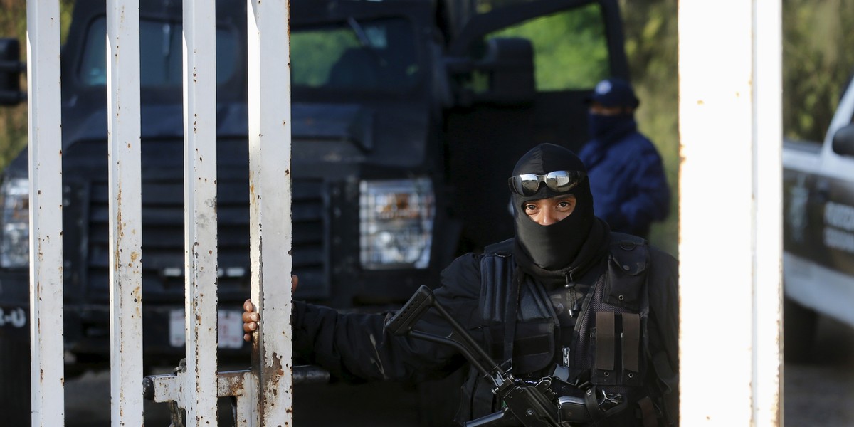 A police officer stands guard at an entrance to a ranch where a firefight took place on Friday in Tanhuato, state of Michoacan, May 23, 2015.