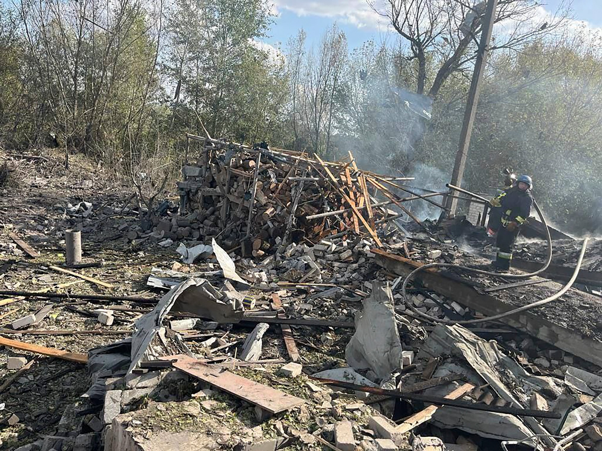Na snímke hasiči hasia požiar po ruskom raketovom útoku na dedinu Hroza v Charkovskej oblasti.