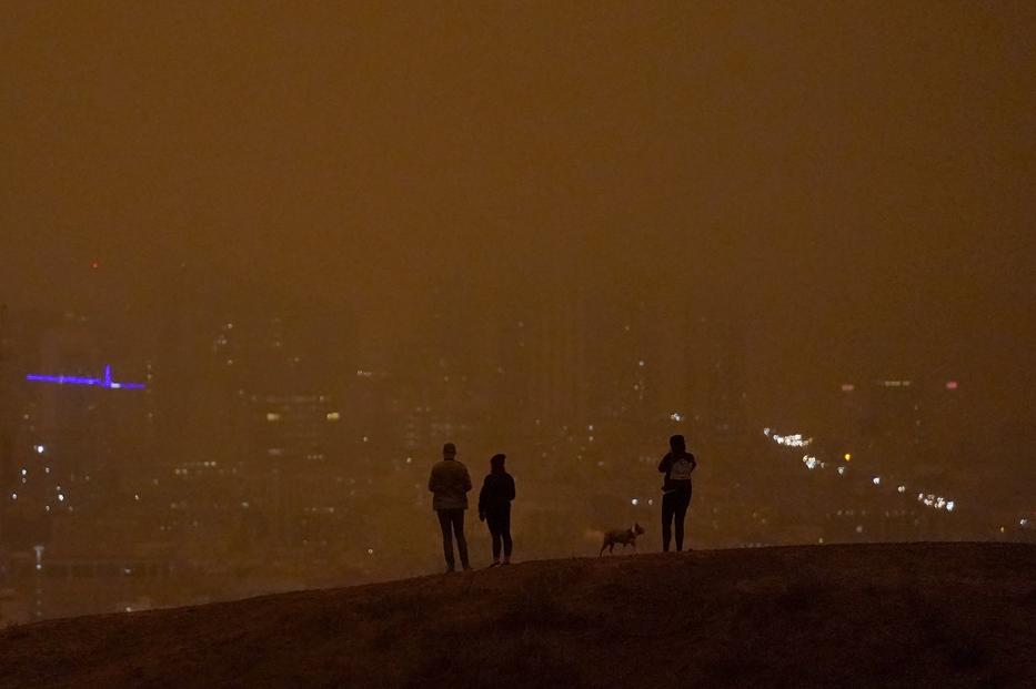 Emberek néznek le egy dombról, de az egész nap égő erdőtűz füstjétől szinte sötét van nappal is San Franciscóban szeptember 9-én / Fotó: MTI/AP/Jeff Chiu 