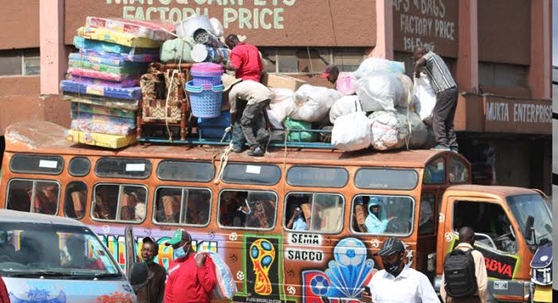 Bus attendants help fasten wares to the top of a matatu at the Machakos Country Bus Station [Photo: Steve MulwawaKi7]
