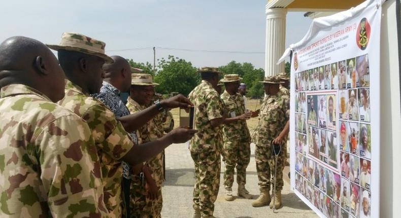 Soldiers look at the Nigerian army's latest list of most wanted Boko Haram members in Maiduguri, northeast Nigeria, on November 21, 2016