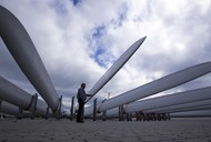 Pracownik ogląda łopaty, które zostaną zamontowane na wiatrakach w Rostocku w Niemczech. fot. Jens Buettner/PAP/DPA.