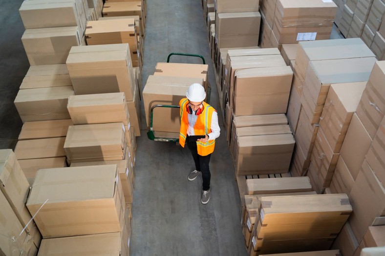 Logistic warehouse worker delivering boxes on a trolley