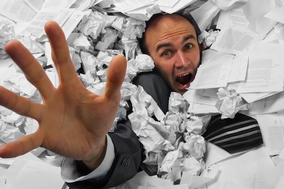 Businessman sinking in heap of documents