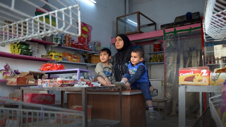 Umm Mustapha, a 27-year-old widow, with her sons in her grocery shop in Iraq's northern city of Mosul on November 28, 2018