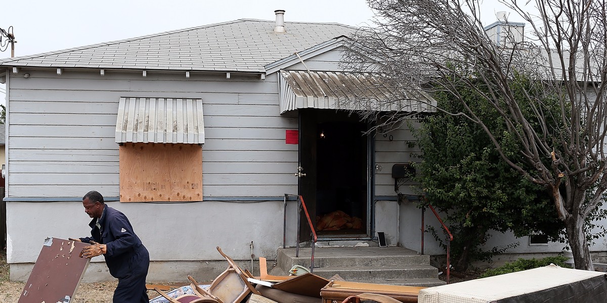 A worker removes furniture from a foreclosed home before the start of a bus tour of foreclosed and blighted properties on July 13, 2012, in Richmond, California.