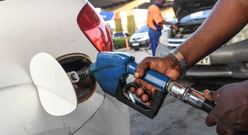 A pump attendant fills a car with fuel.