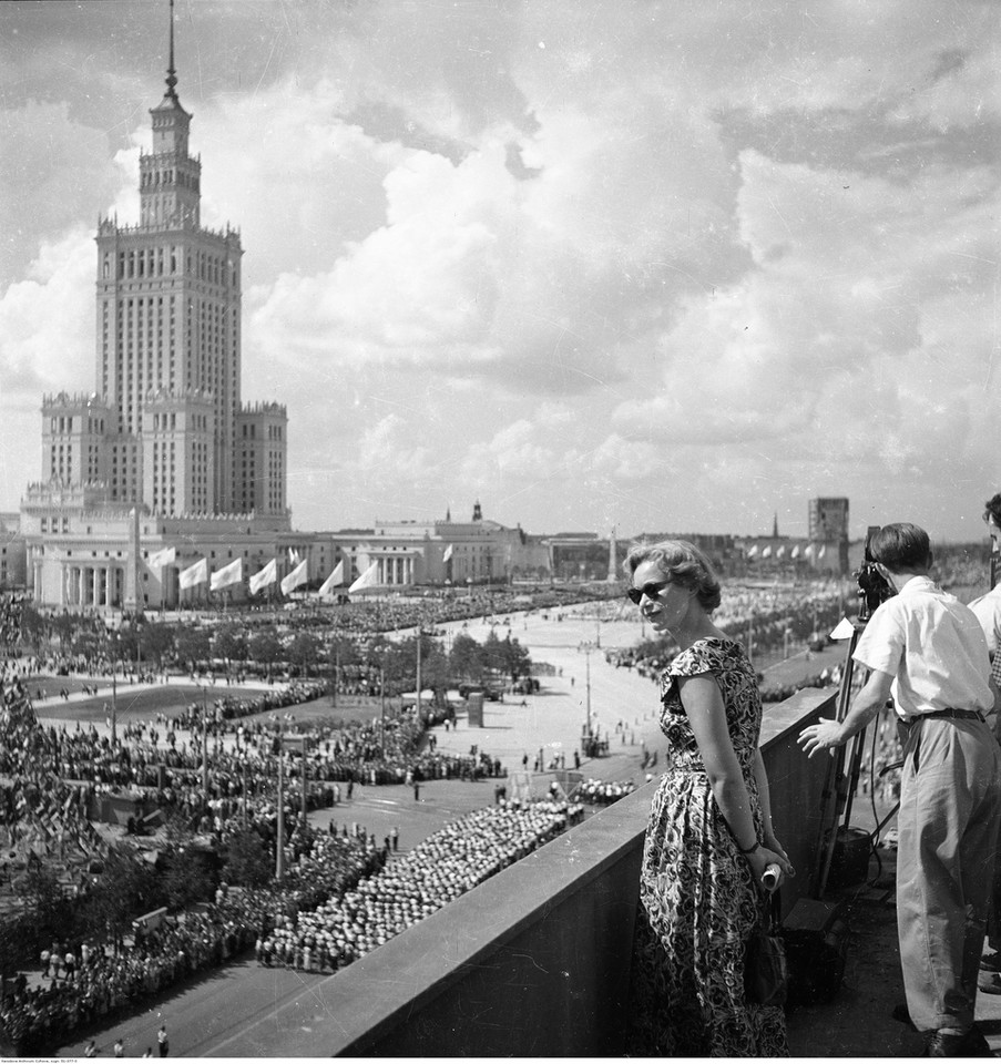 Pałac Kultury i Nauki oraz plac Defilad - widok z dachu budynku przy ulicy Marszałkowskiej. Widoczna młodzież idąca w pochodzie ulicą Marszałkowską. Lipiec/sierpień 1955 r. 