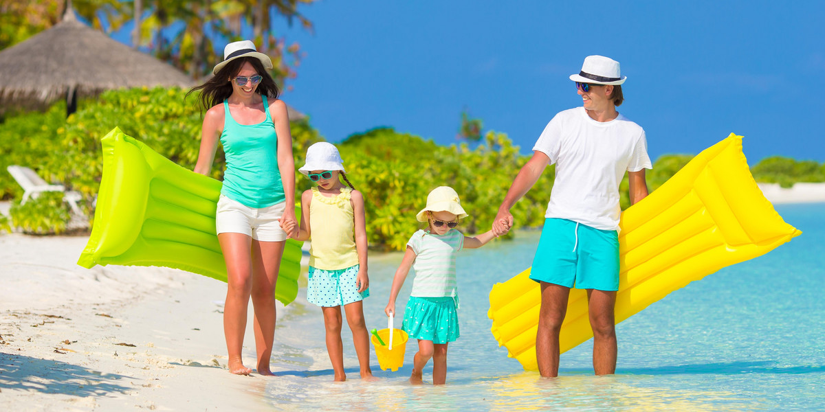 Happy beautiful family on white beach with inflatable air mattresses