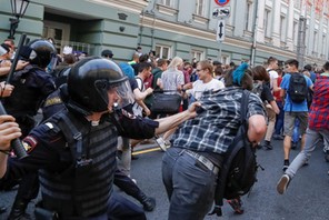 Police officers chase protesters during a rally against planned increases to the nationwide pension 