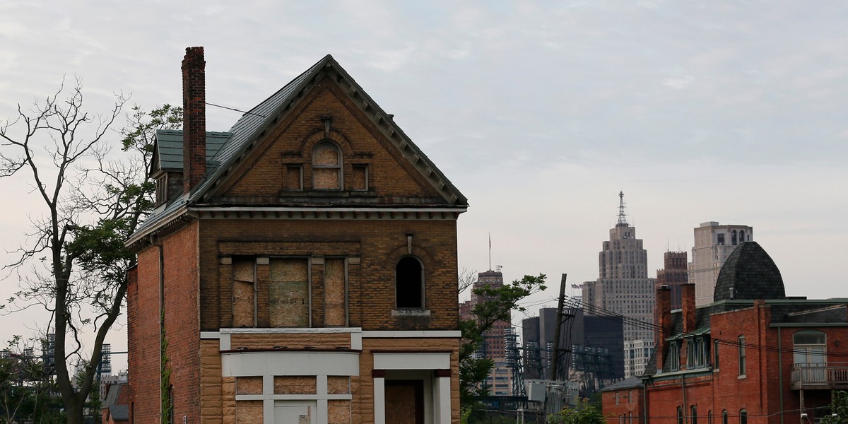 A boarded-up vacant home is seen with General Motors World Headquarters, left, and the Detroit skyline on June 10, 2014.