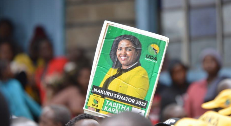 A supporter hold up a poster for UDA's Nakuru Senator aspirant Tabitha Karanja Keroche