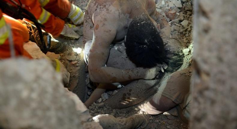 Rescuers save three-year-old Wu Ningxi, who was protected by the body of her dead father more than 12 hours after four buildings collapsed in Wenzhou, eastern China on October 10, 2016