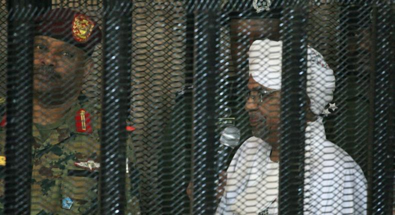 Sudan's deposed president Omar al-Bashir stands in a defendant's cage during the opening of his corruption trial in Khartoum last August