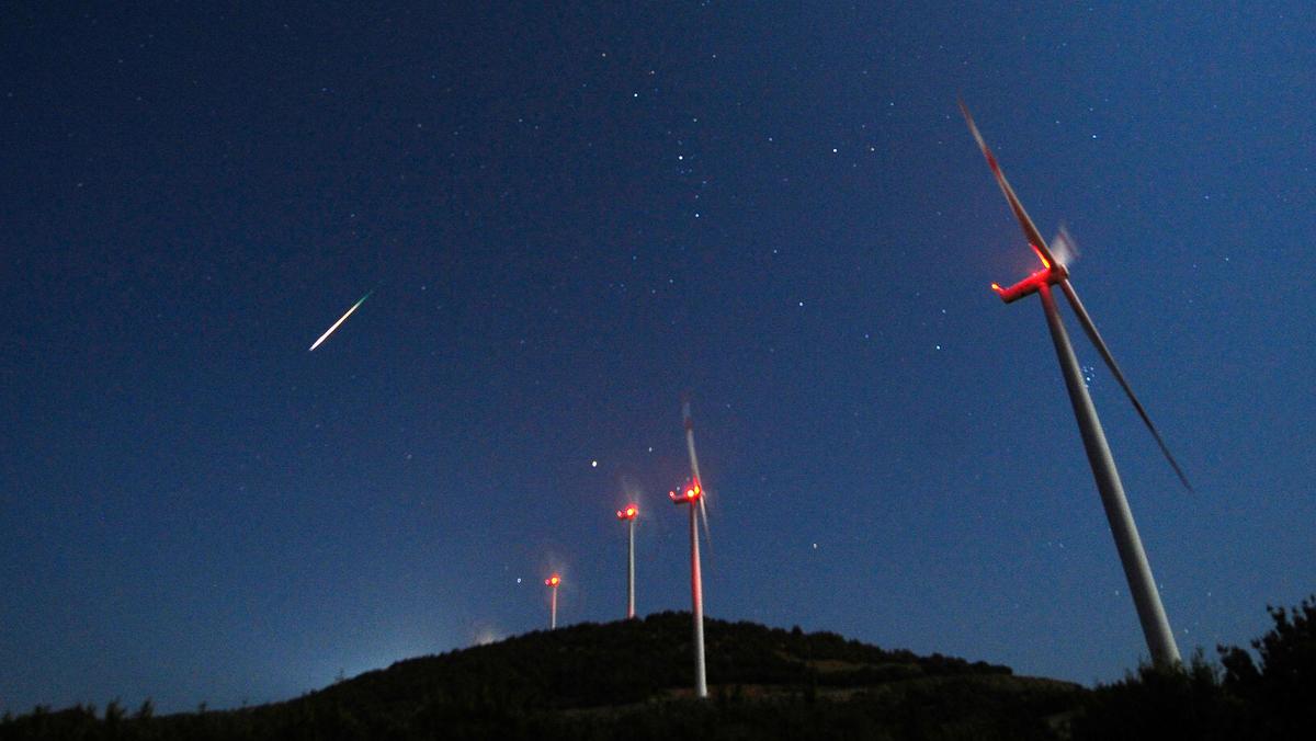 A meteor streaks across the sky during the Perseid meteor shower at a windmill farm near Bogdanci