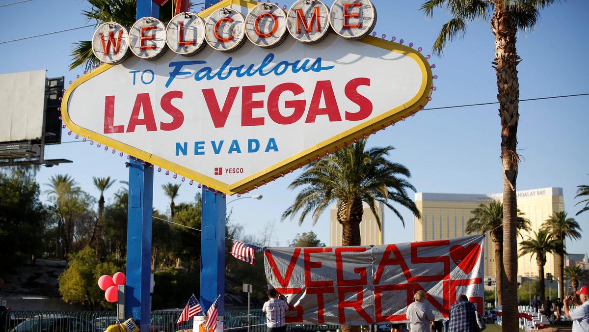 People sign a banner near the Welcome to Fabulous Las Vegas sign following the Route 91 music fest