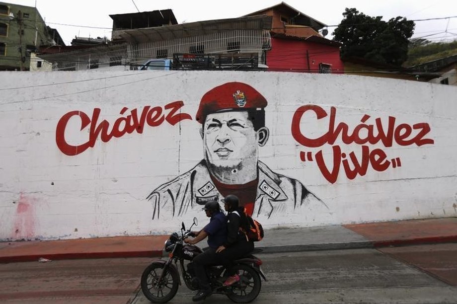 A motorcycle rides past a mural depicting late Venezuelan President Hugo Chavez, near his mausoleum in Caracas.