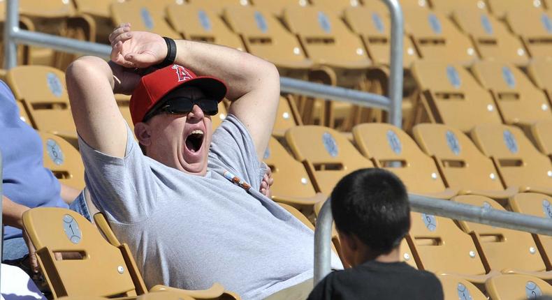 A baseball fan yawns during a game.