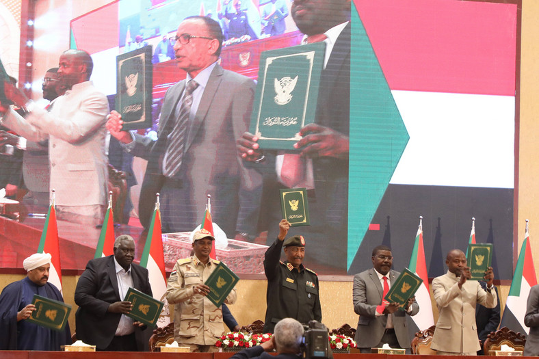 Abd al-Fattah (czwarty od lewej), Mohamed Hamdan Dagalo (trzeci od lewej) i przywódcy grup cywilnych, trzymają podpisane dokumenty porozumienia ramowego mającego na celu zakończenie impasu politycznego w Chartumie. 5 grudnia 2022 r.