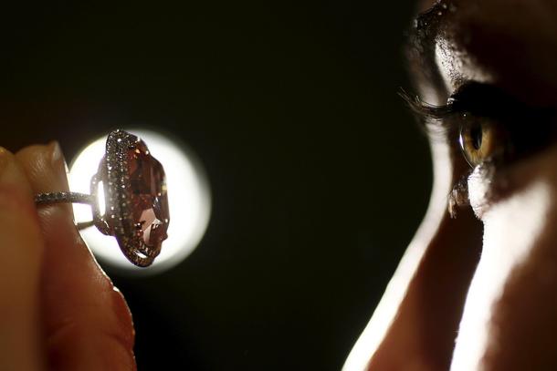 An employee poses with a cushion-shaped 16.08 carat vivid pink diamond at Christie's auction house i