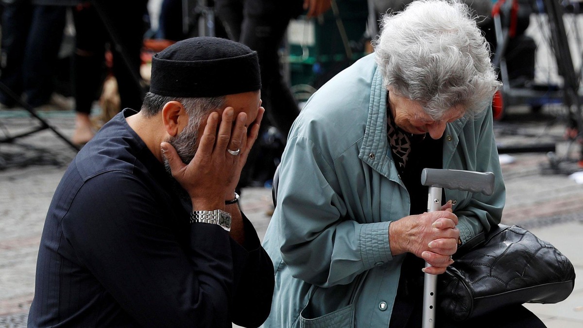 A Jewish woman named Renee Rachel Black and a Muslim man named Sadiq Patel react next to floral trib