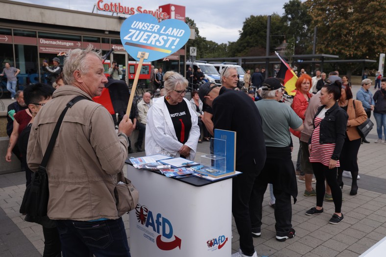 Un voluntar din partidul de extremă dreapta Alternativa pentru Germania distribuie pliante la o întâlnire de marcare a Zilei Unității Germane în orașul Cottbus, 3 octombrie 2023.