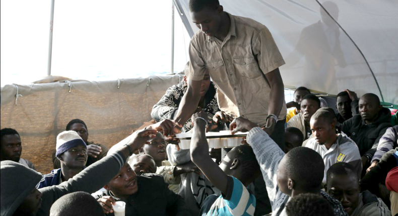Des migrants se partagent une boisson dans de petites tasses
