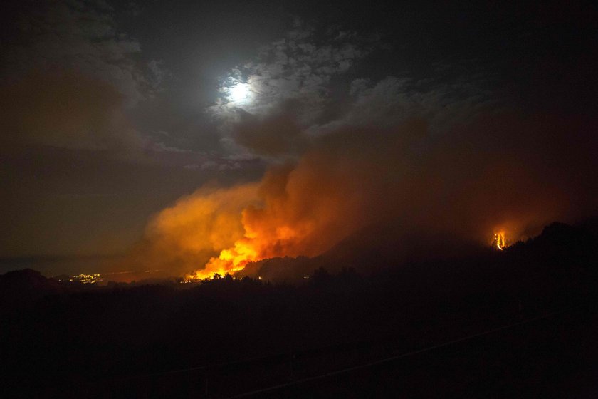 Flames and smoke from a forest fire are seen in the village of Valleseco