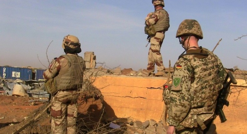 Soldiers of the Barhkane operation stand next to debris following a suicide car bomb attack at the airport of Gao on November 30, 2016