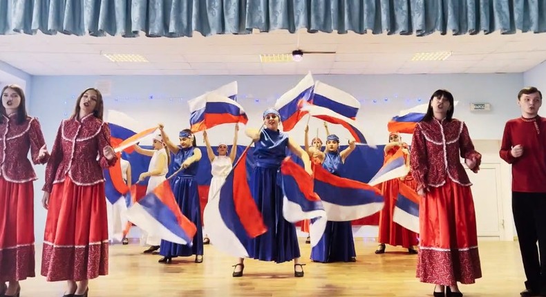 A screengrab circulated by Russia's Ministry of Education, showing Ukrainians in the occupied Donetsk region dancing and singing the Russian national anthem and waving the Russian flag.Russian Ministry of Education