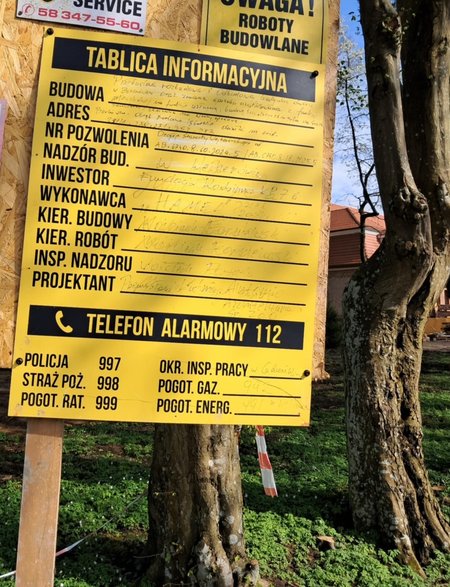 Budowlana tablica informacyjna przed dworkiem Obajtka