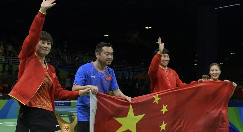 (L-R) China's Ding Ning, coach Kong Linghui, Li Xiaoxia and Liu Shiwen posing with the national Chinese flag after winning gold medals in the women's team final table tennis at the Riocentro venue during the Rio 2016 Olympic Games in Rio de Janeiro