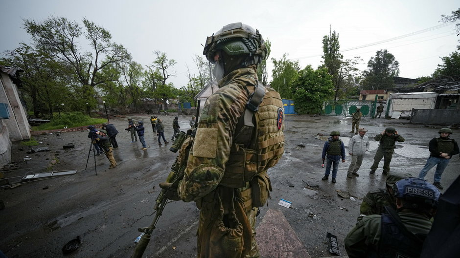 Rosyjski żołnierz pilnuje terenu, podczas gdy międzynarodowi dziennikarze zwiedzają zniszczoną część zakładów metalurgicznych Illich Iron & Steel Works w Mariupolu (zdjęcie ilustracyjne)