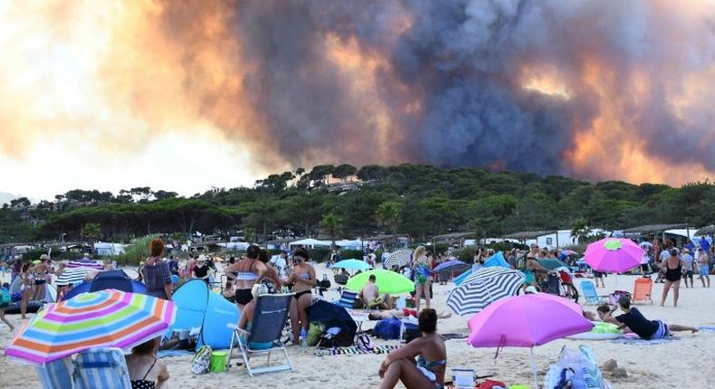 People watch from the beach as smoke billows into the sky over Bormes-les-Mimosas