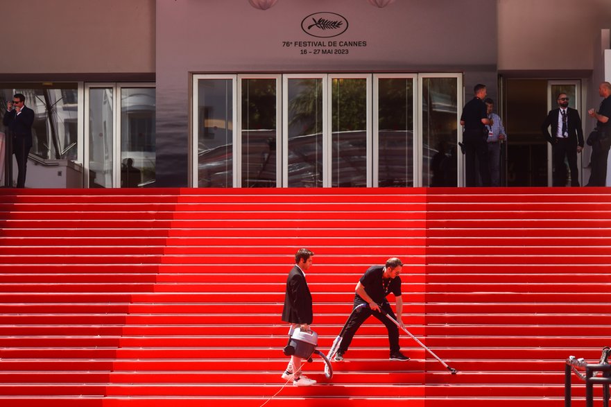 Personel czyści czerwony dywan przed wejściem do Palais des Festivals w Cannes, 24 maja 2023 r.