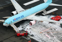 An aerial picture shows firefighters spraying foam at the engine of a Korean Air Lines plane after smoke rose from it at Haneda airport in Tokyo