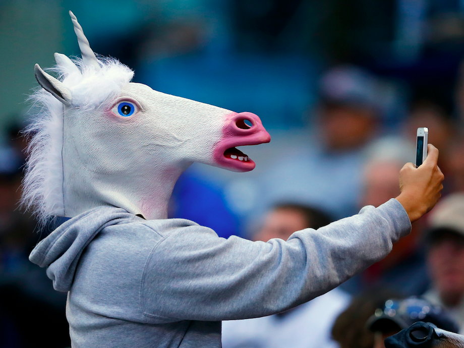 A baseball fan wearing a unicorn mask takes a picture of himself with his phone as he attends the Interleague MLB game between the San Diego Padres and the Toronto Blue Jays in San Diego, California June 2, 2013.
