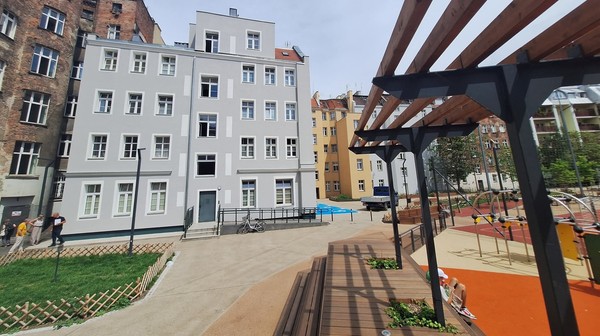 Elewacja, która wcześniej nie miała nawet tynku, zyskała nowe oblicze - jasną kolorystykę i zielone akcenty. Całość dopełniają eleganckie, białe naczółki okienne, które podkreślają charakter obiektu. 