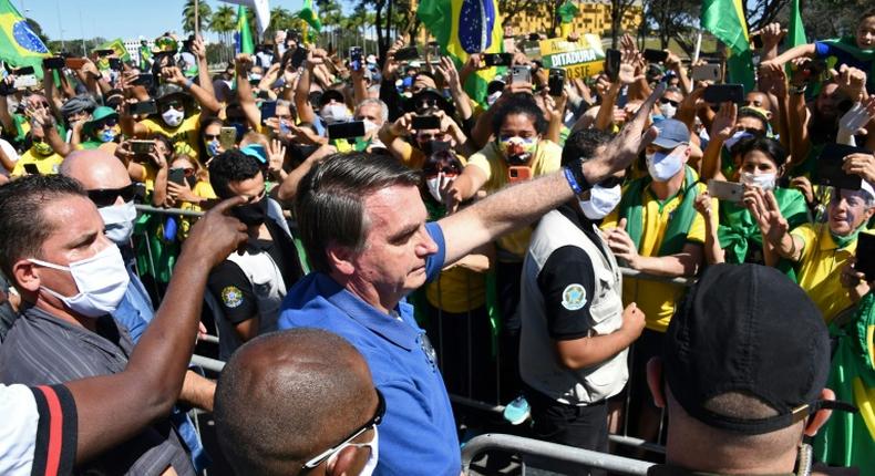 Brazilian President Jair Bolsonaro (C) has opposed lockdown measures